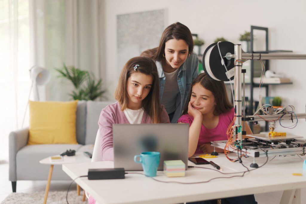 Smart girls learning 3D printing at home, their sister is helping them, education and science concept